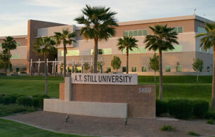 Entrance to ATSU's Mesa, Arizona campus featuring a brick sign posted in front of palm trees.
