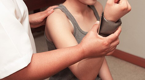 Occupational therapist examining the wrist of a young woman.