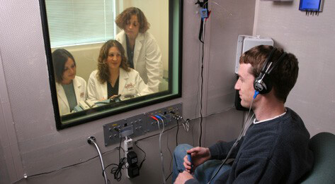 Audiology students facilitating hearing test in clinical training environment.