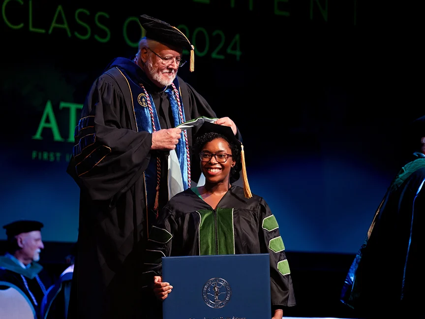 ATSU DMSc graduate receiving an academic hood on stage during the commencement ceremony