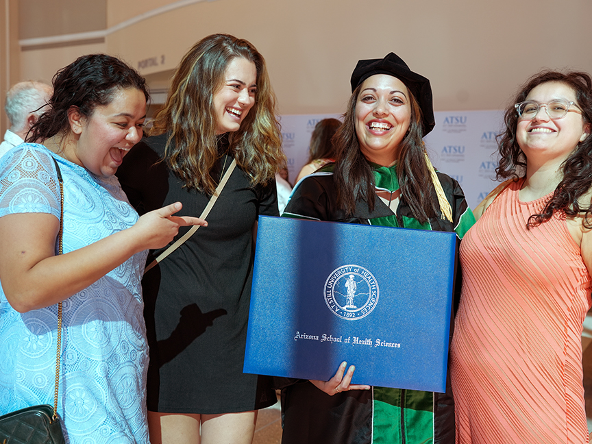 ATSU DMSc graduate holding her diploma and taking a photo with friends