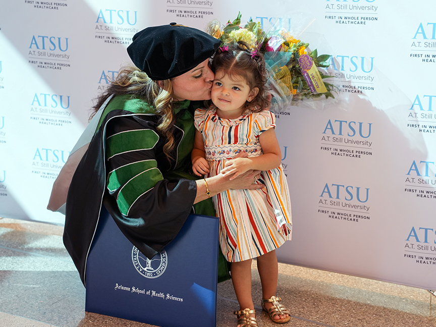ATSU DMSc graduate kissing a young family member at graduation