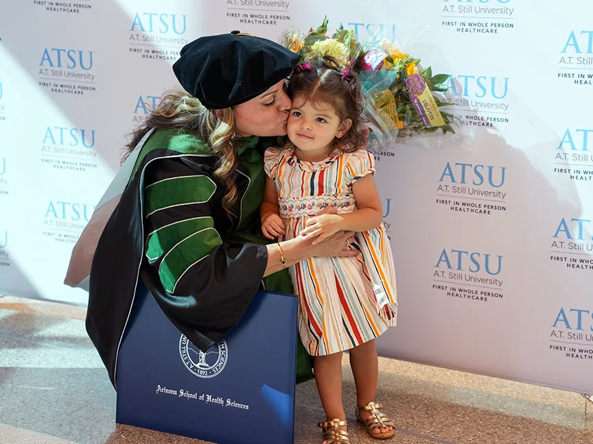 ATSU DMSc graduate kissing a young family member at graduation