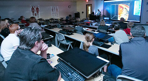 Students sitting in a lecture hall listening to a presentation.
