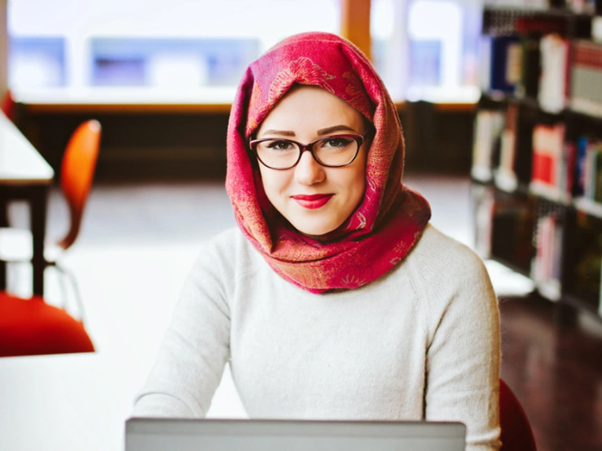 ATSU Audiology student smiling at the camera while working on a computer