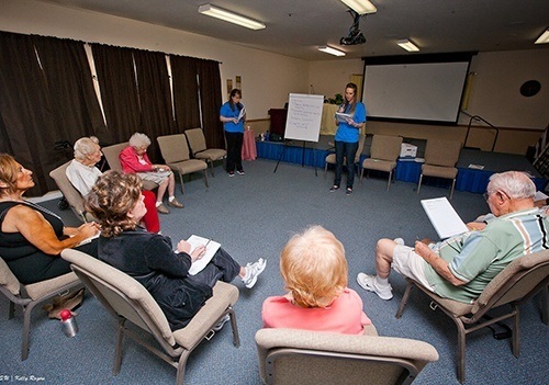 Female ATSU audiology student giving a presentation to a group of elderly people.