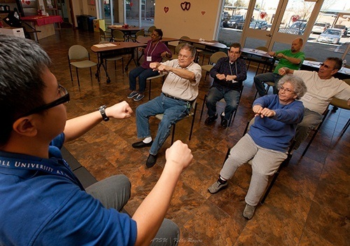 Audiology workshop featuring participants seated with their arms stretched out in front of them.