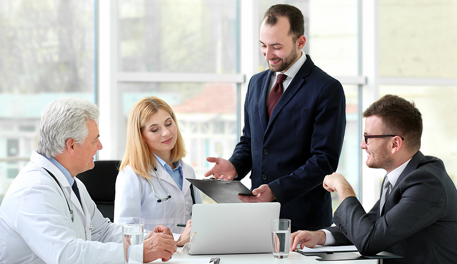 Doctors and business men around laptop smiling