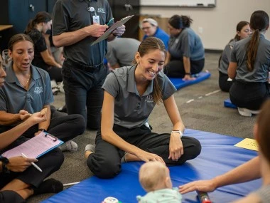 MSOT student sitting down and smiling while helping children