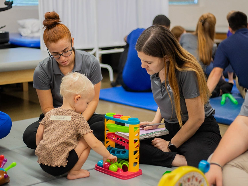 Two OT students helping child build blocks