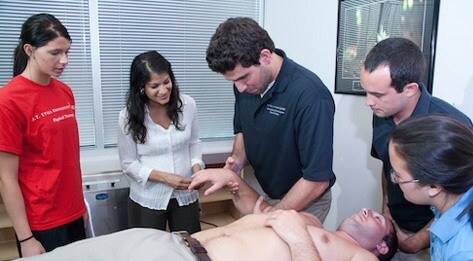 Group of ATSU Physical Therapy students examining a man lying shirtless on a patient table.