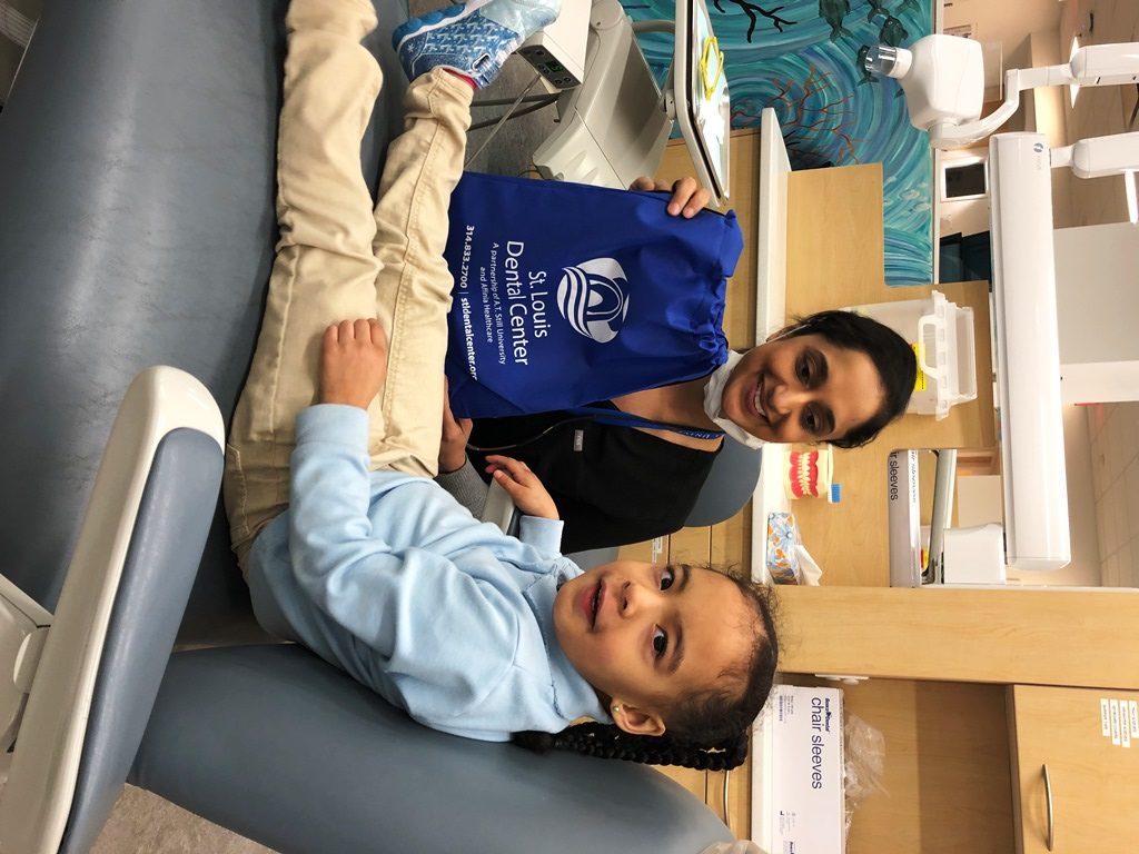 Dentist with young patient holding sports bag