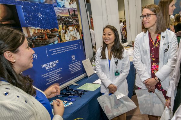 Two students talk to a hospital representative.