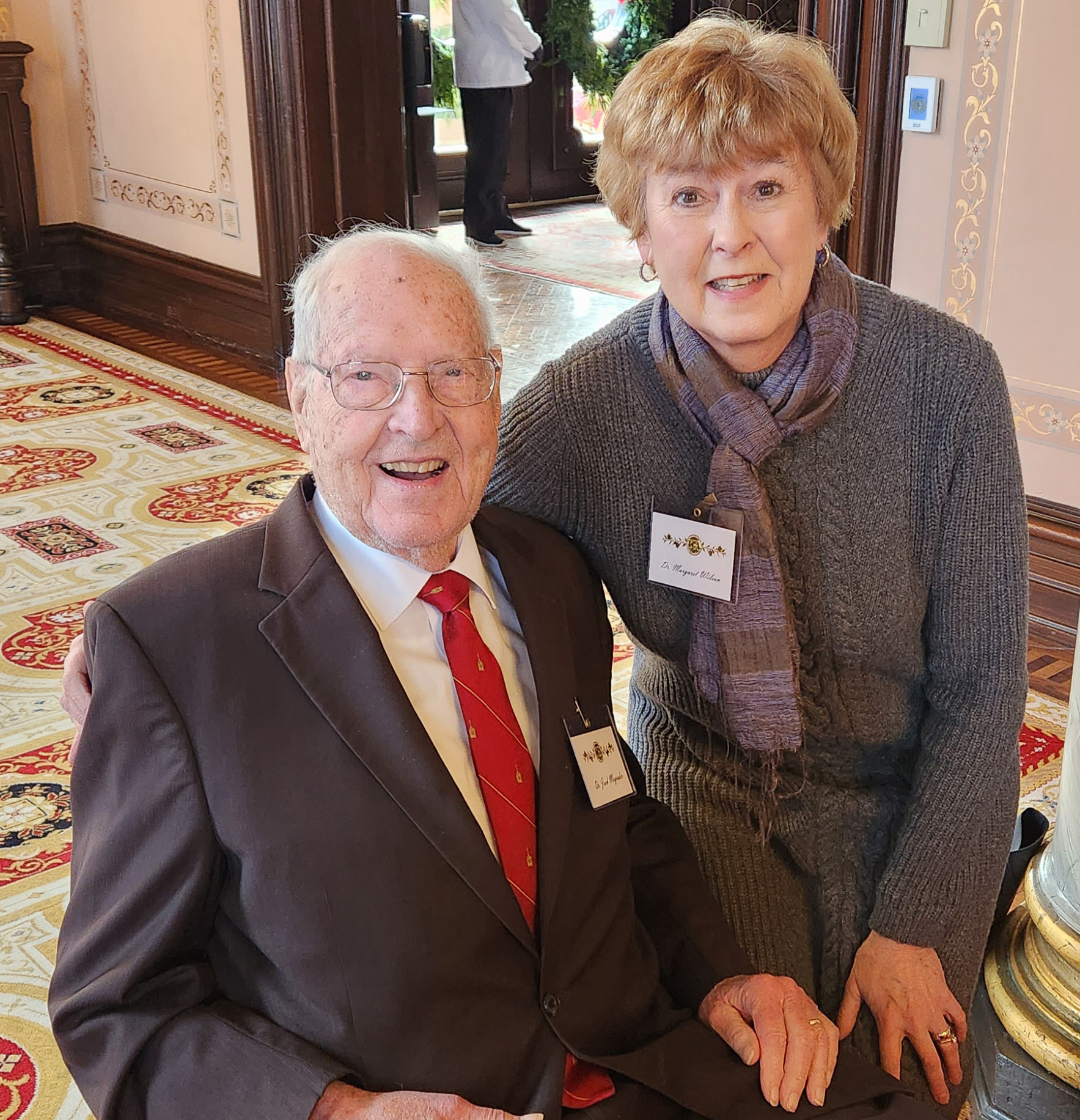 Two individuals pose for a photograph inside the governor's mansion.