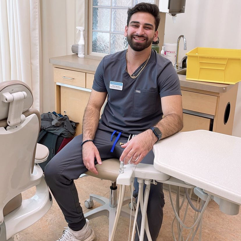 Omar Yaacoobi, D3, sits in a dental lab seat, surrounded by dental equipment