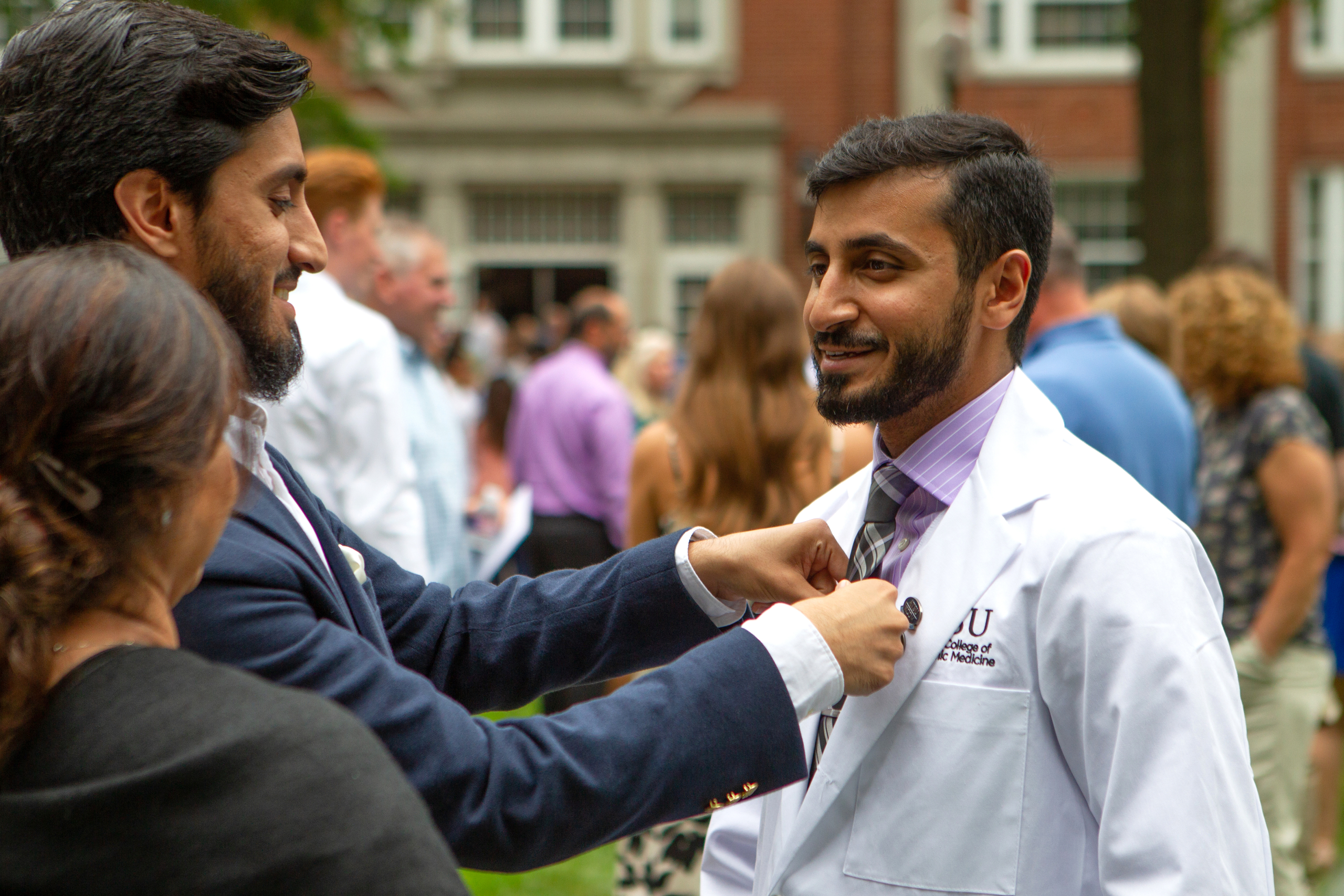 An ATSU-KCOM student has his tie straightened by a family member after the White Coat Ceremony.