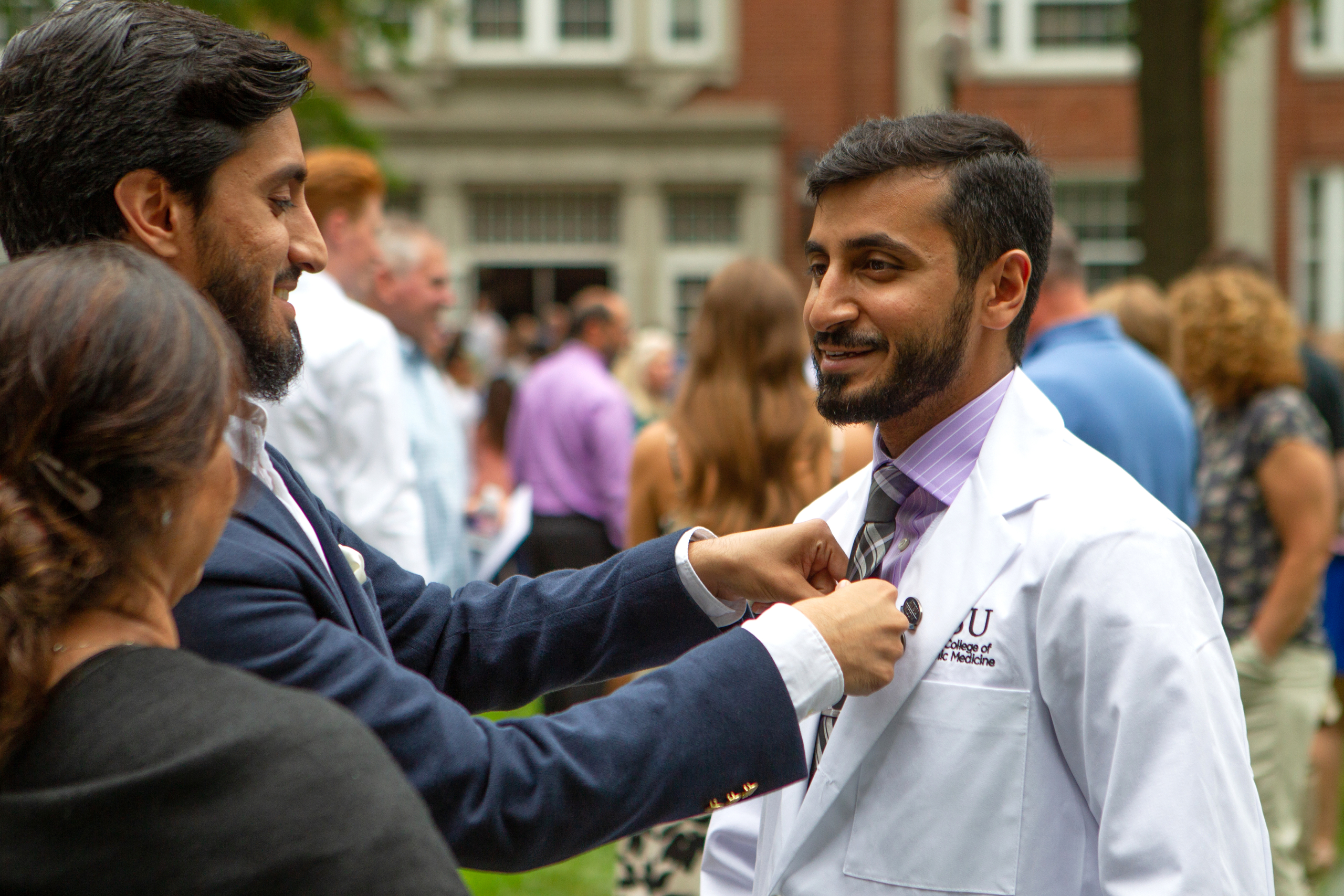 An ATSU-KCOM student has his tie straightened by a family member after the White Coat Ceremony.