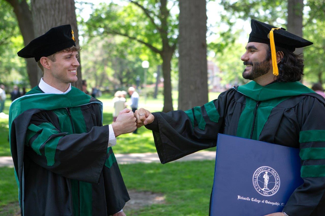 Two students fist bump following ATSU-KCOM commencement.