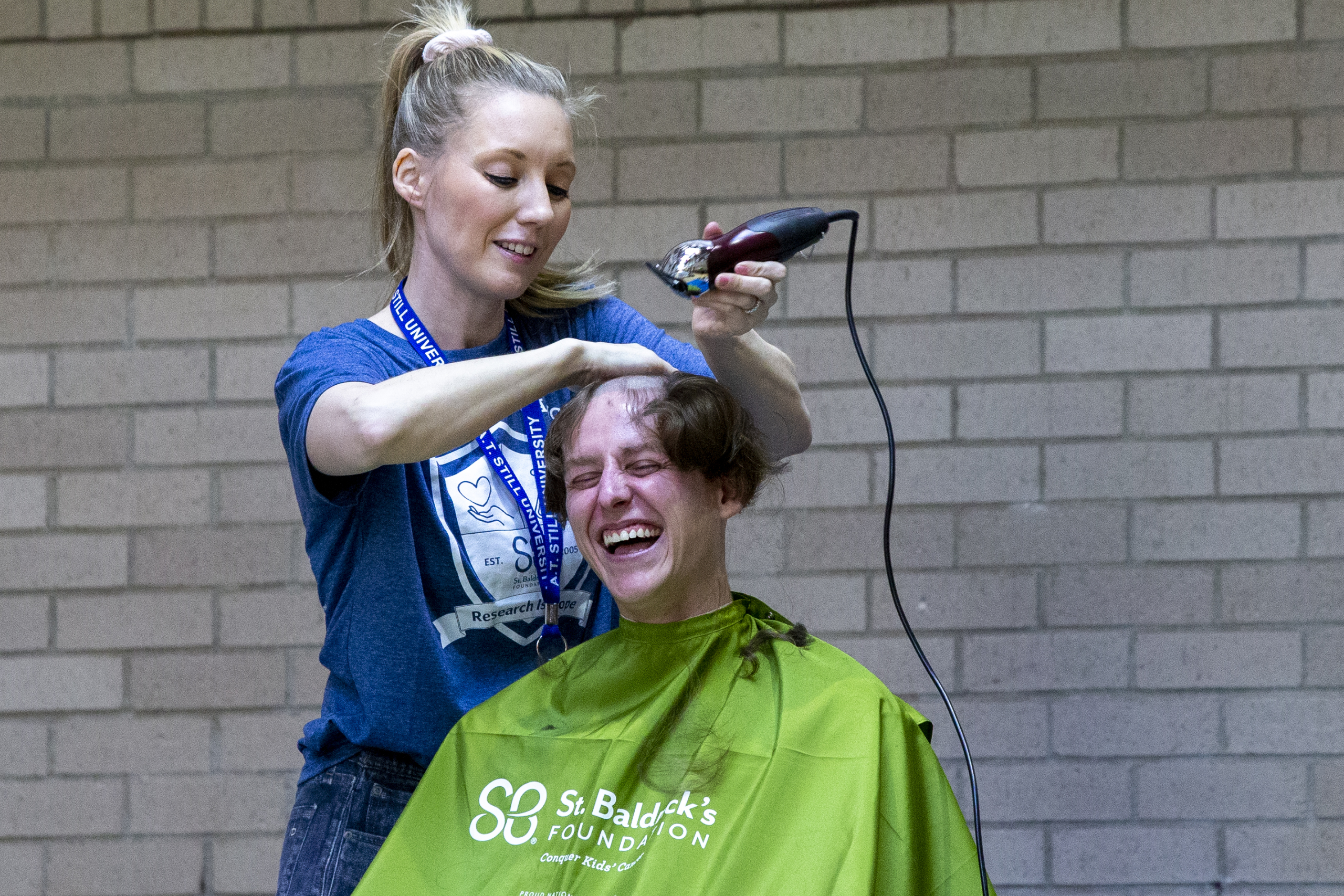 An individual smiles as his head is shaved during an event to benefit childhood cancer research