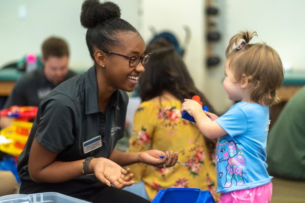 Physical therapy student plays blocks with a child at the annual Baby Lab