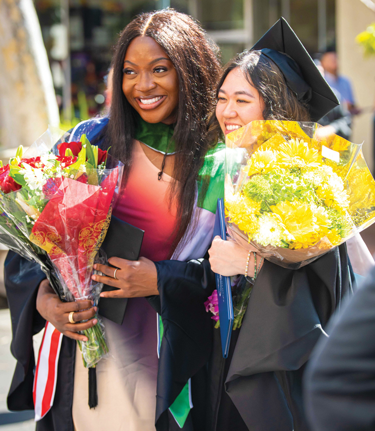 two graduates with flowers