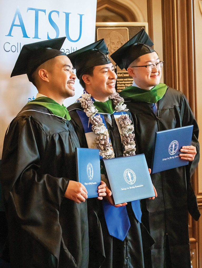 three graduates with diplomas