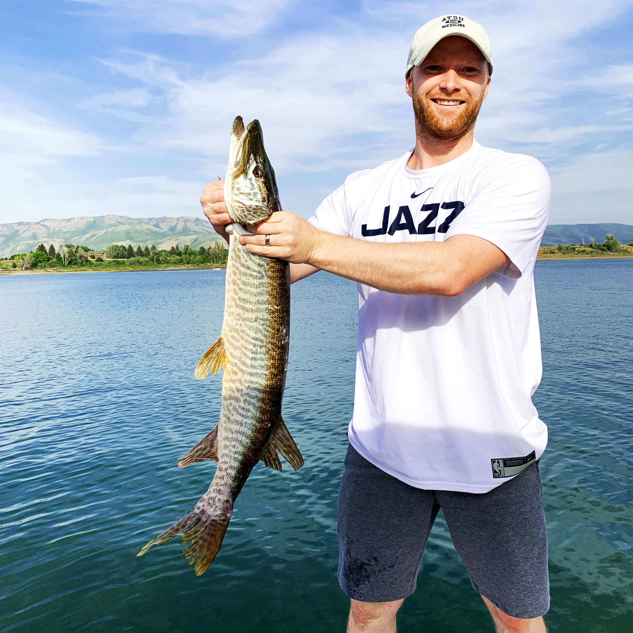 A man is holding a large fish. The fish is longer than the man's entire upper body.