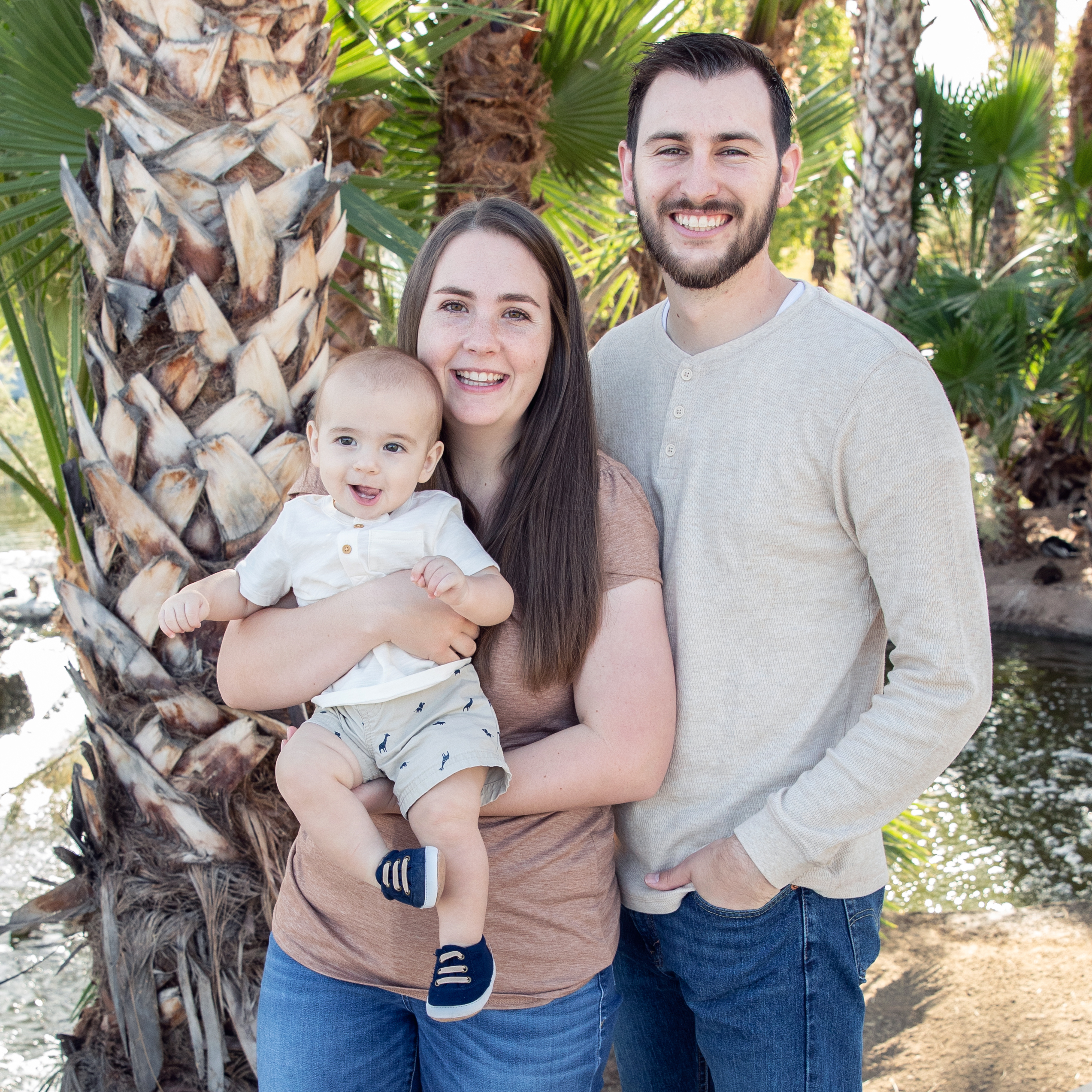 A man poses with his wife and child.