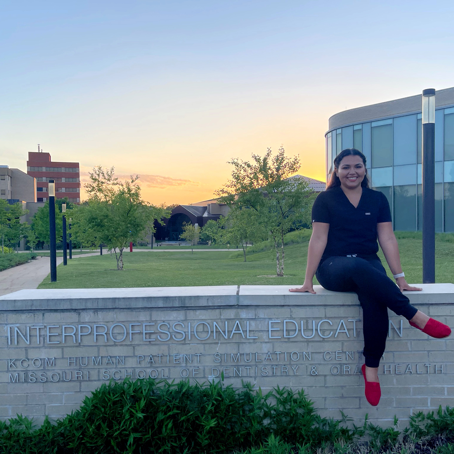 An ATSU-MOSDOH student sits on campus with the setting sun just beyond view on the horizon.