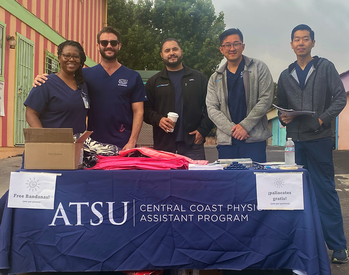 ATSU-CHC students stand at a table with bandanas and flyers in this posed picture.