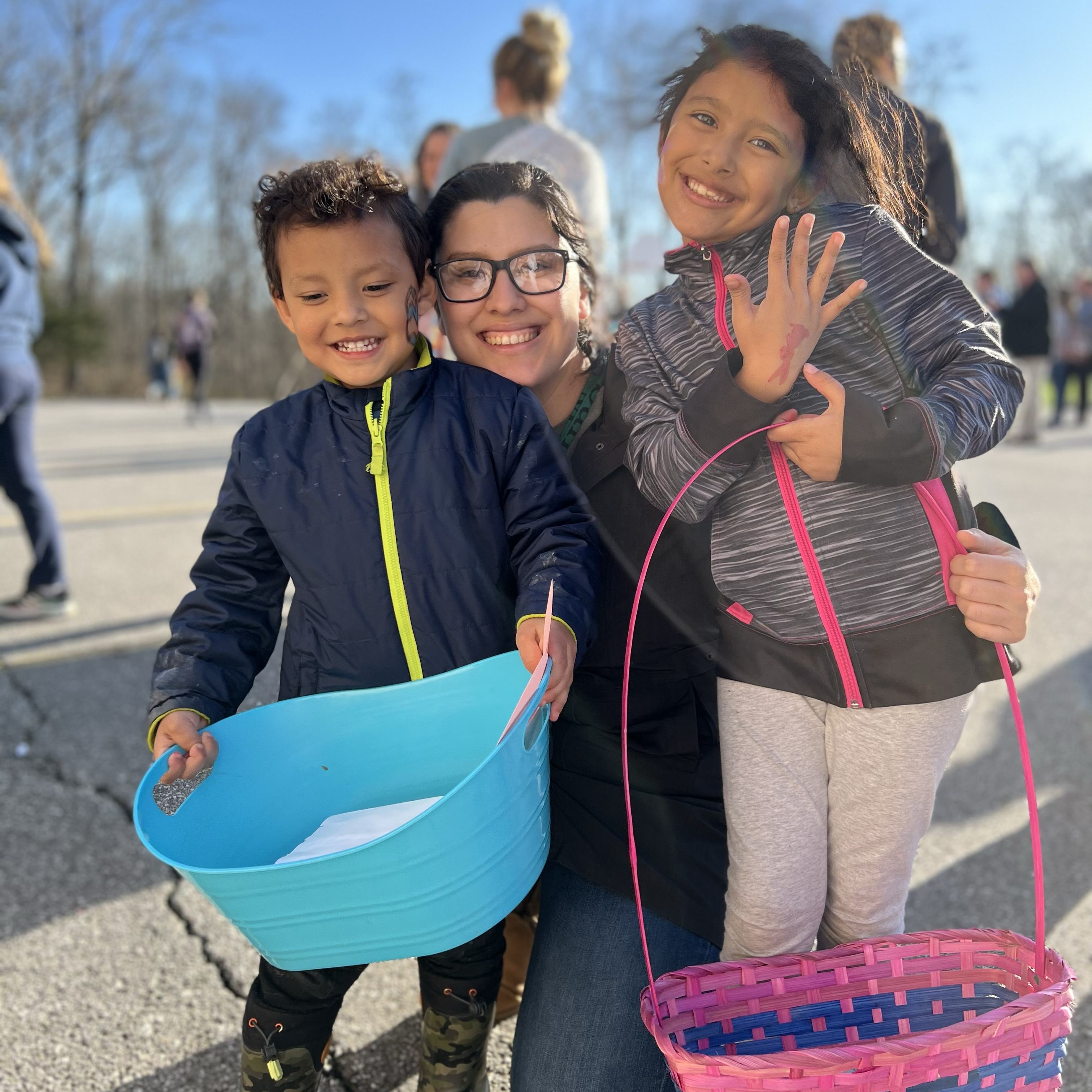 Two children pose with an adult during an Easter egg hunt event.