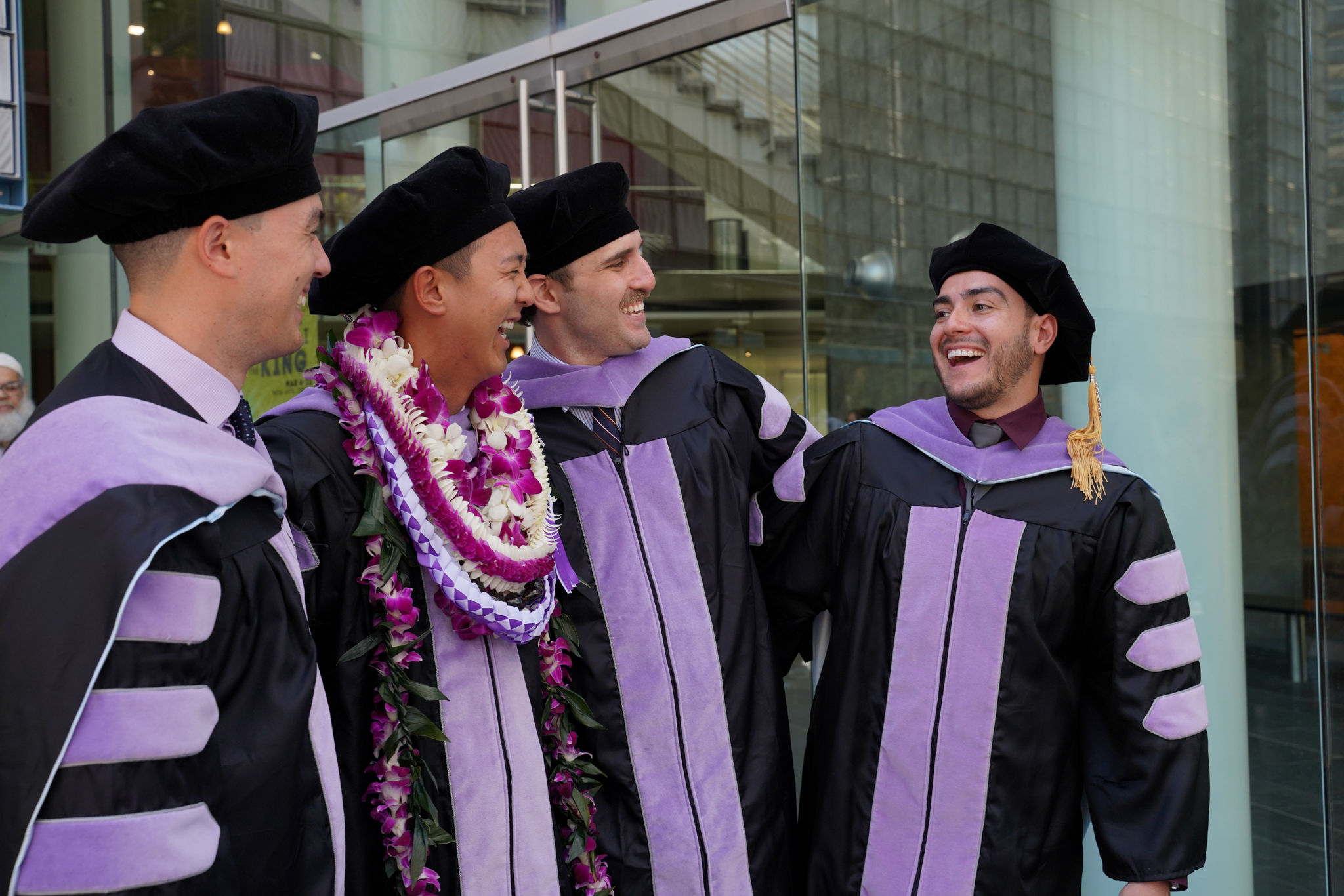Four ATSU-ASDOH graduates gather and smile following commencement.