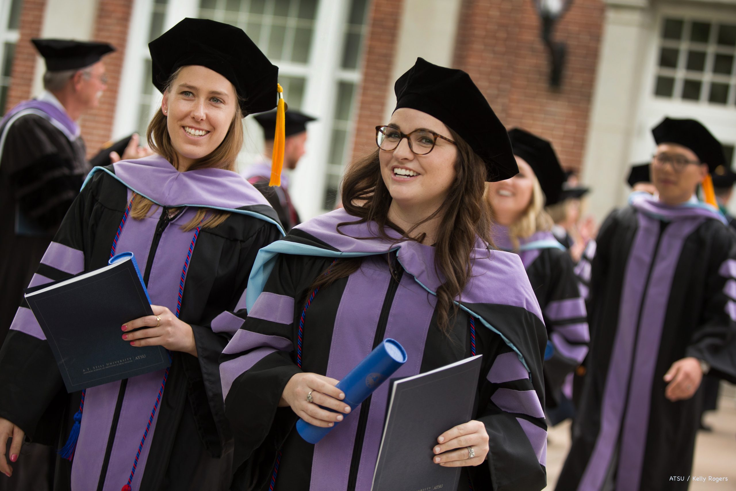 Graduates walk out of Baldwin Hall Auditorium holding their diploma.