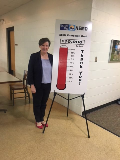 Trish Sexton, ATSU United Way Campaign chairman, stands next to a sign showing the campaign goal was met.