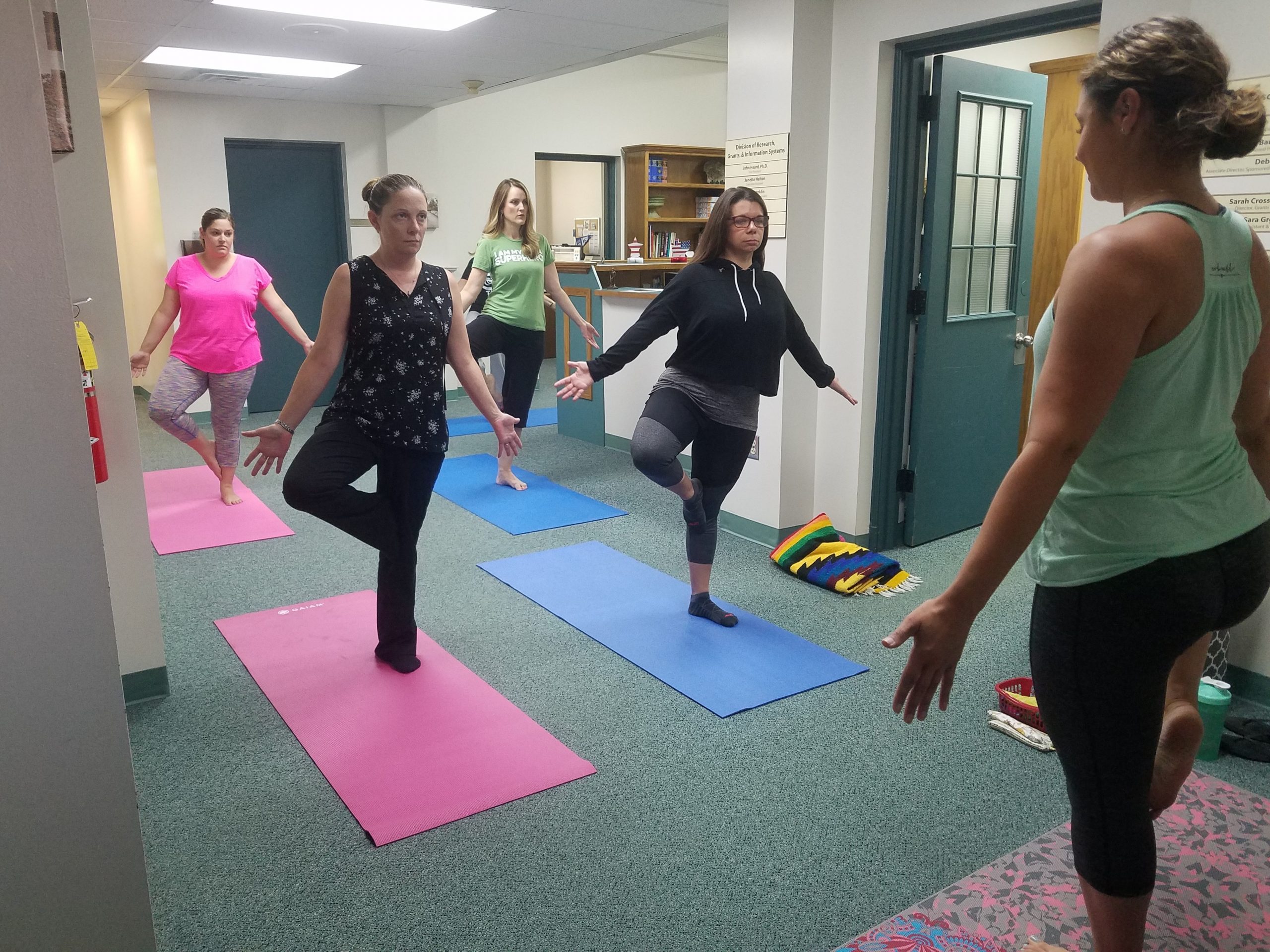 Females in office doing yoga pose