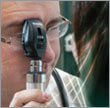Man looking through an ophthalmoscope.