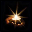 Lit tea candle in the palm of a human hand.